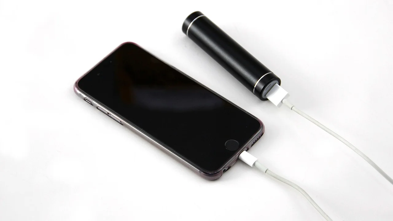 Celular conectado ao carregador em uma superfície ventilada.