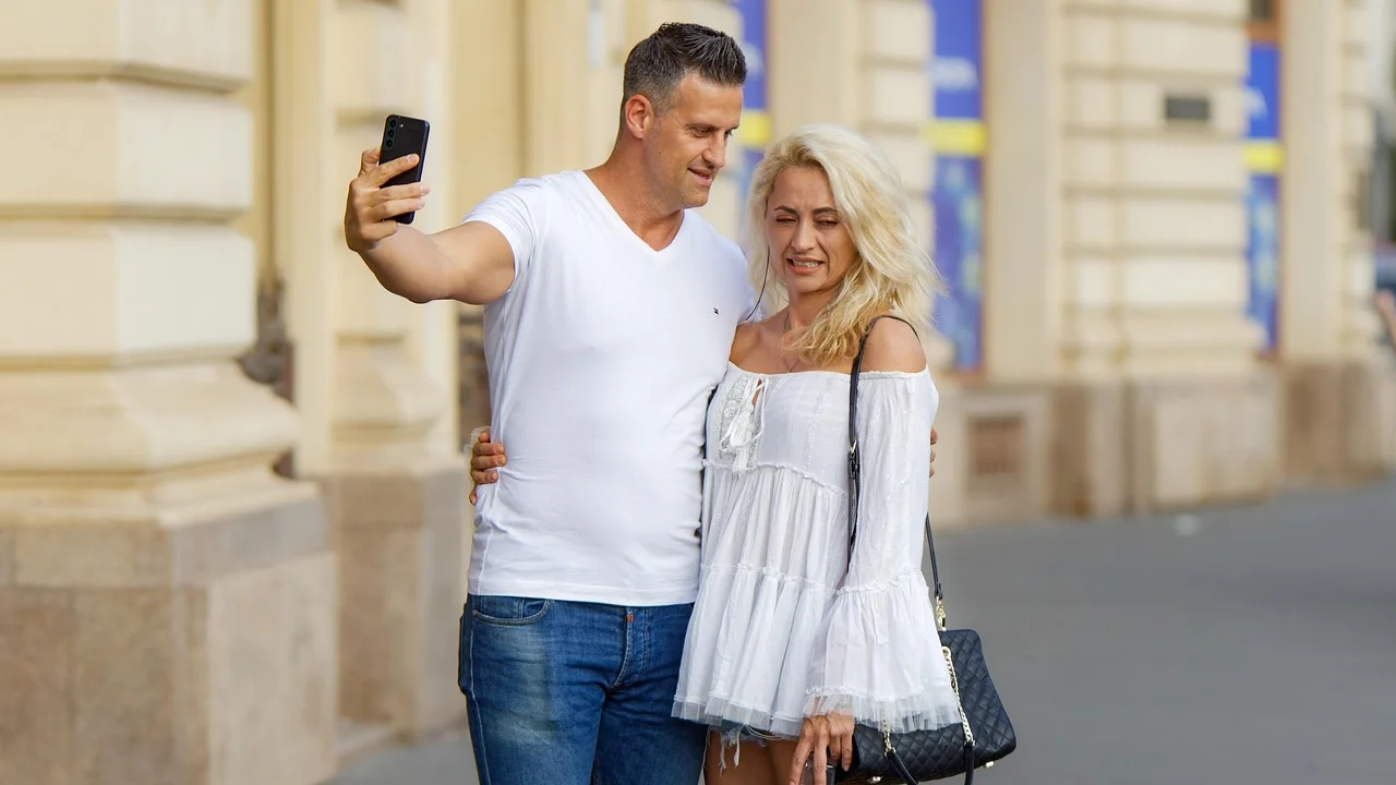Casal sorrindo enquanto vê mensagens no smartphone.