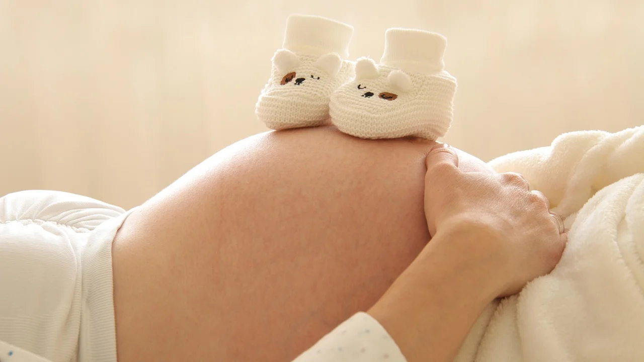 Bebê recém-nascido dormindo enrolado em uma manta clara.