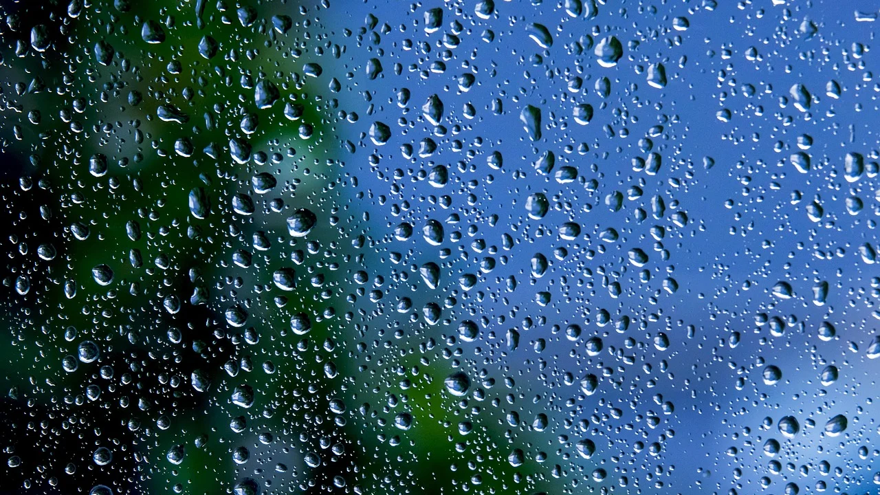 Gotas de chuva escorrendo pelo vidro de uma janela.